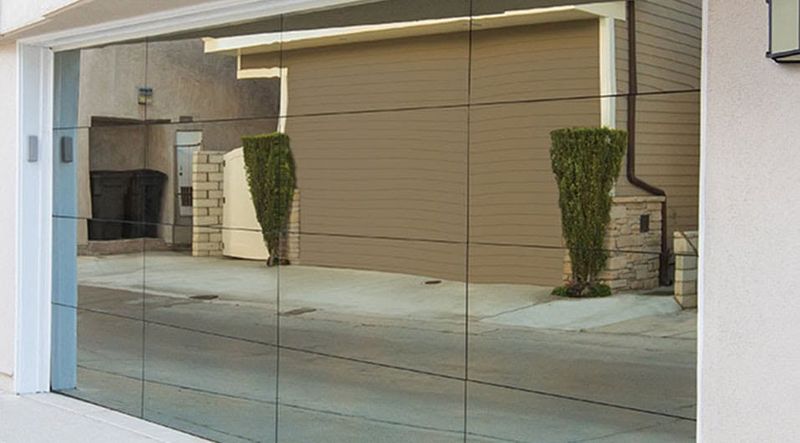 Modern full-view garage door with mirrored glass panels reflecting the street