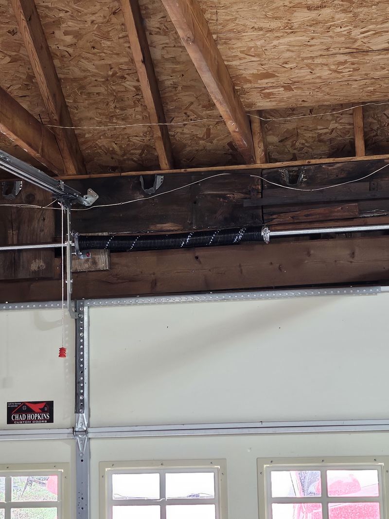 New torsion spring mounted on the header above a white garage door